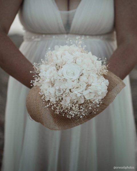Bouquet rond en fleurs séchées blanches, avec roses, hortensias et gypsophile, tenu par une mariée - Les pensées de Lily