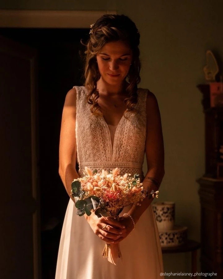Mariée en robe ivoire tenant un bouquet de fleurs séchées au coucher du soleil - Les pensées de Lily