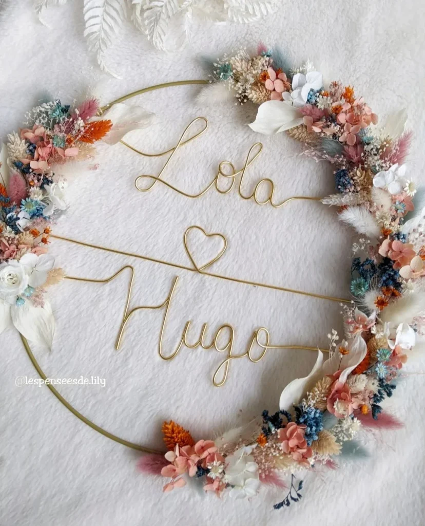 Couronne murale en fleurs séchées colorées, personnalisée avec les prénoms Lola et Hugo en fil doré et un cœur au centre - Les Pensées de Lily"