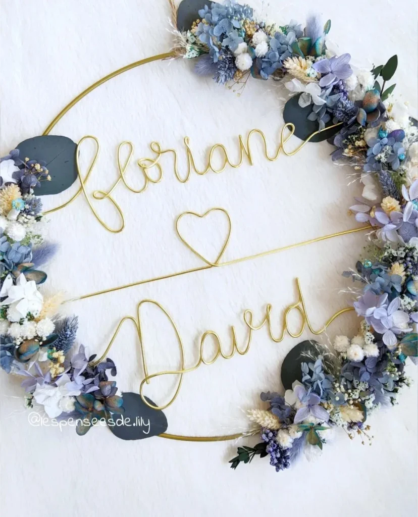 Couronne murale en fleurs séchées bleu, blanc et violet, personnalisée avec les prénoms Floriane et David en fil doré et un cœur au centre - Les Pensées de Lily