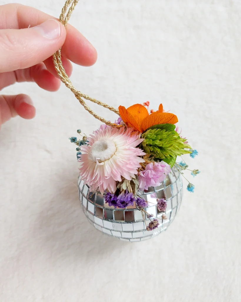 Boule à facettes décorée de fleurs séchées colorées, tenue par un cordon doré, avec un mélange de textures brillantes et naturelles - Les pensées de Lily