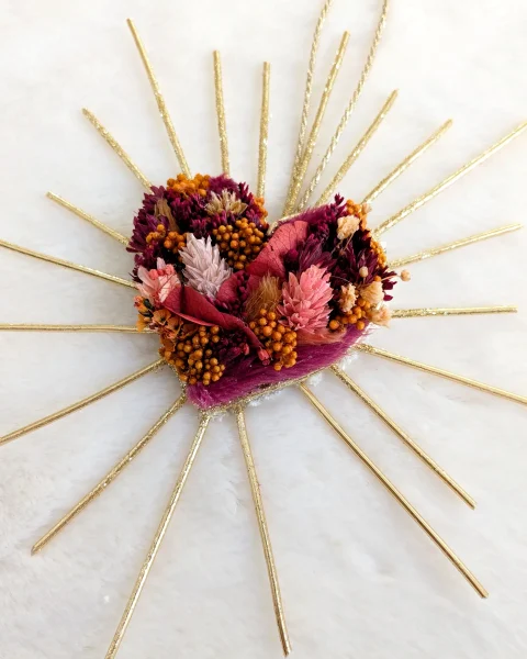 Gros plan d’un cœur en fleurs séchées terracotta et roses avec rayons dorés, sur fond blanc – Les pensées de Lily
