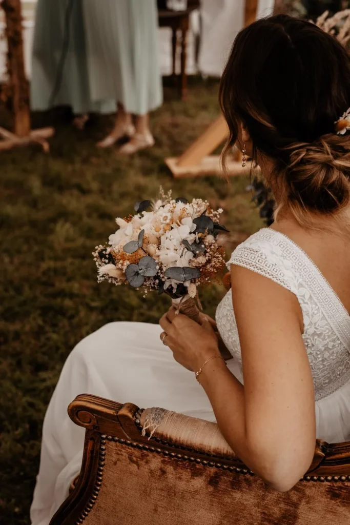 Mariée assise tenant un bouquet de fleurs séchées ivoire, jaune et eucalyptus bleu-gris - Les pensées de Lily