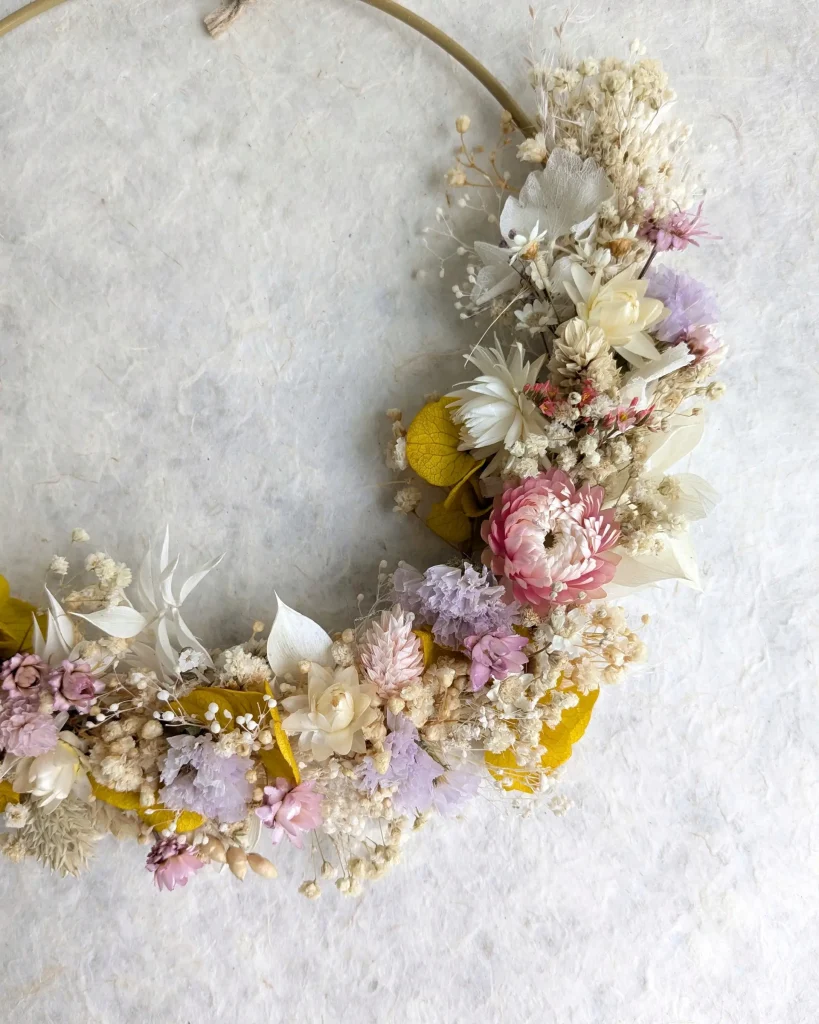 Couronne murale en fleurs séchées aux tons jaune, rose et violet sur cercle doré avec lien en corde naturelle - Les pensées de Lily