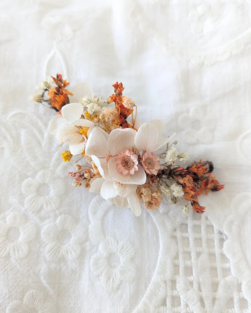 Peigne décoratif en fleurs séchées tons terracotta et ivoire, présenté sur un tissu en dentelle - Les pensées de Lily