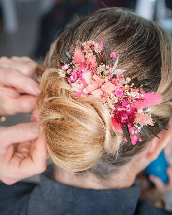Coiffure de mariée avec chignon bas et peigne floral en fleurs séchées rose vif et feuillage vert - Les pensées de Lily