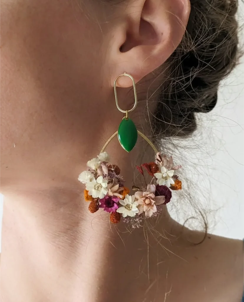 Boucle d’oreille en fleurs séchées crème, bordeaux et orange avec pendentif vert portée à l’oreille - Les pensées de Lily