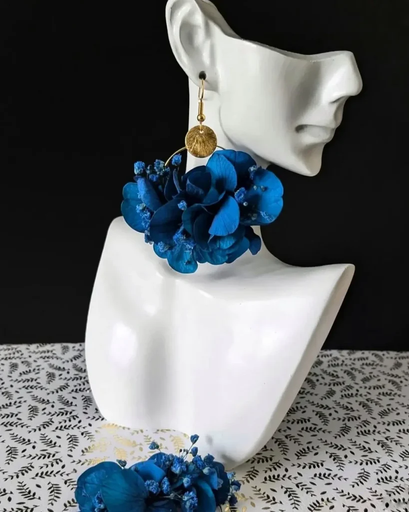 Boucles d’oreilles en fleurs séchées bleu roi avec pastille dorée martelée, portées sur buste blanc - Les pensées de Lily