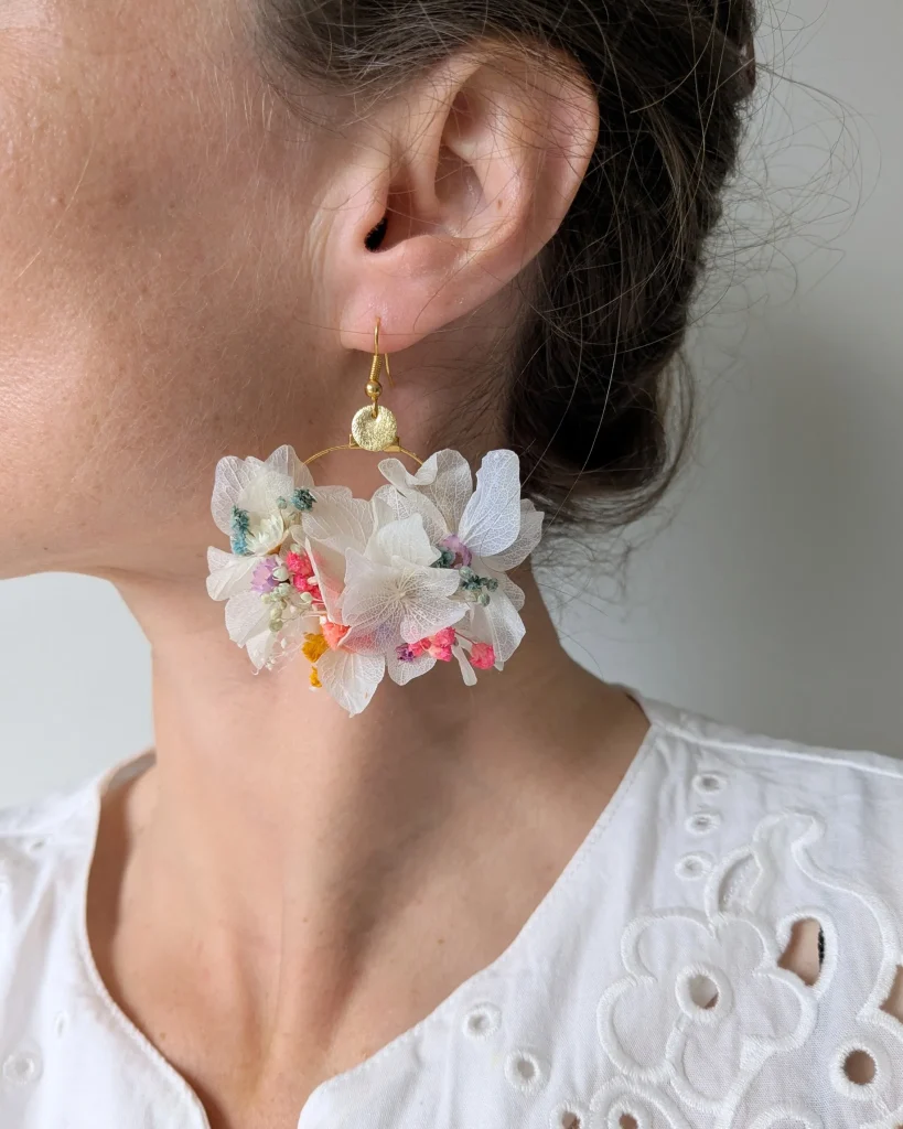 Boucles d’oreilles Confettis en fleurs séchées blanches avec touches colorées, portées sur oreille adulte - Les pensées de Lily