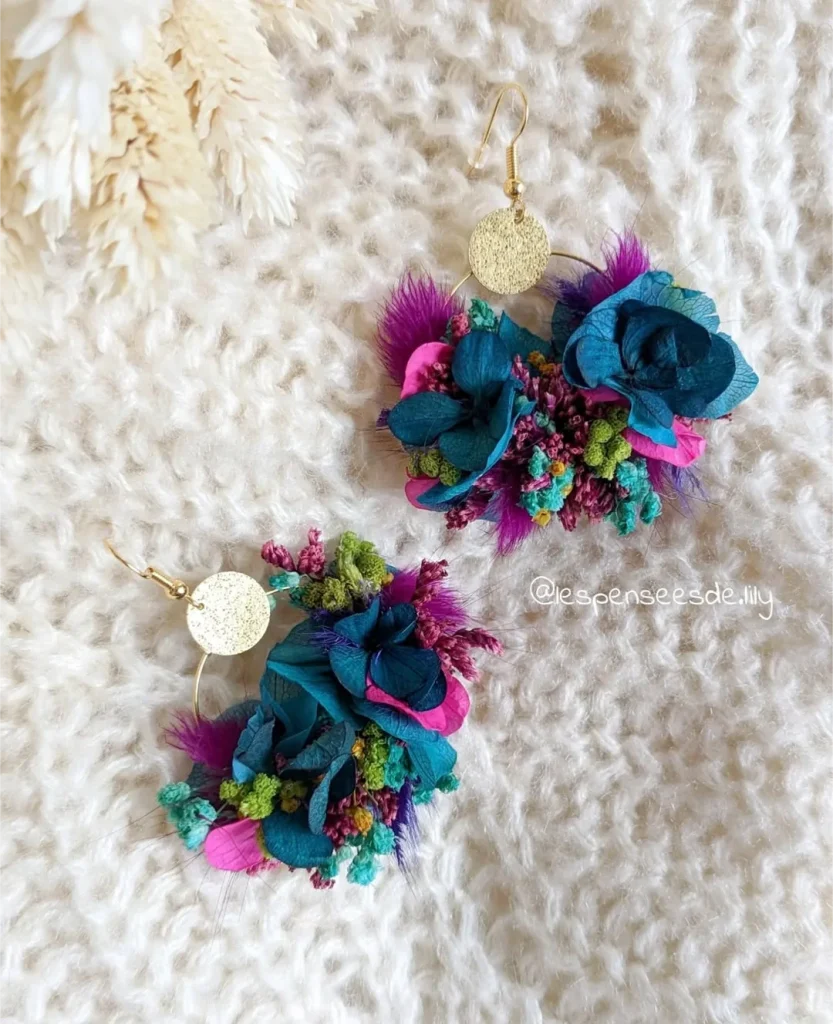 Boucles d’oreilles en hortensia bleu canard avec fleurs séchées violettes, turquoise, fuchsia et vert fluo posées sur fond laineux - Les pensées de Lily