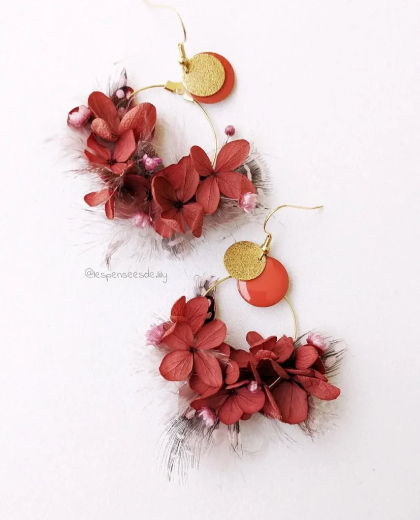 Boucles d’oreilles en hortensia rouge et fleurs séchées roses avec plumes décoratives sur fond blanc - Les pensées de Lily