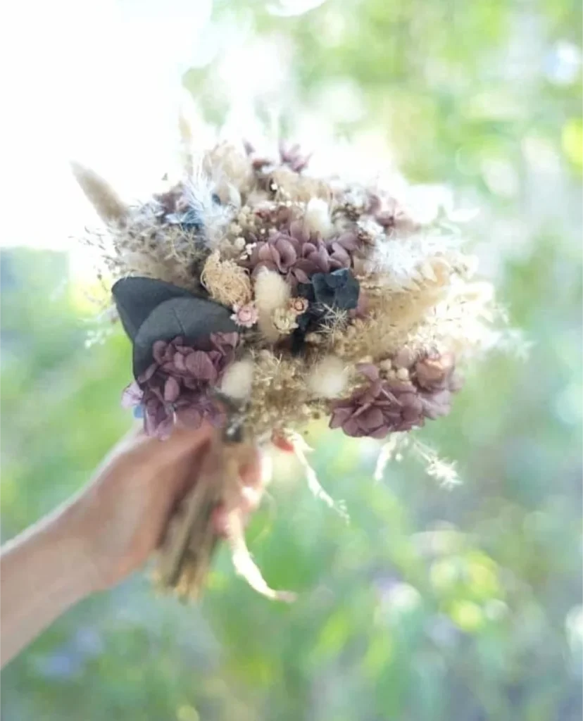 Bouquet de fleurs séchées tons beige, blanc et violet foncé tenu à bout de bras - Les pensées de Lily