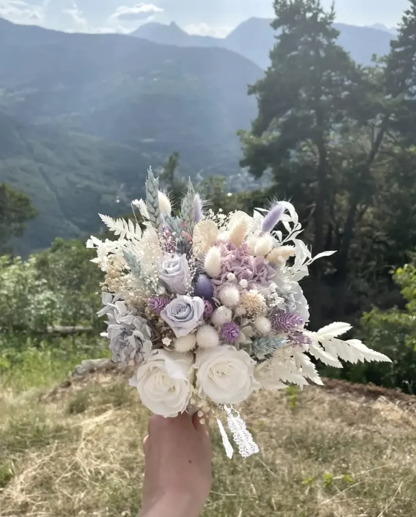 Bouquet de mariée en fleurs séchées blanches et violettes tenu en montagne - Les pensées de Lily