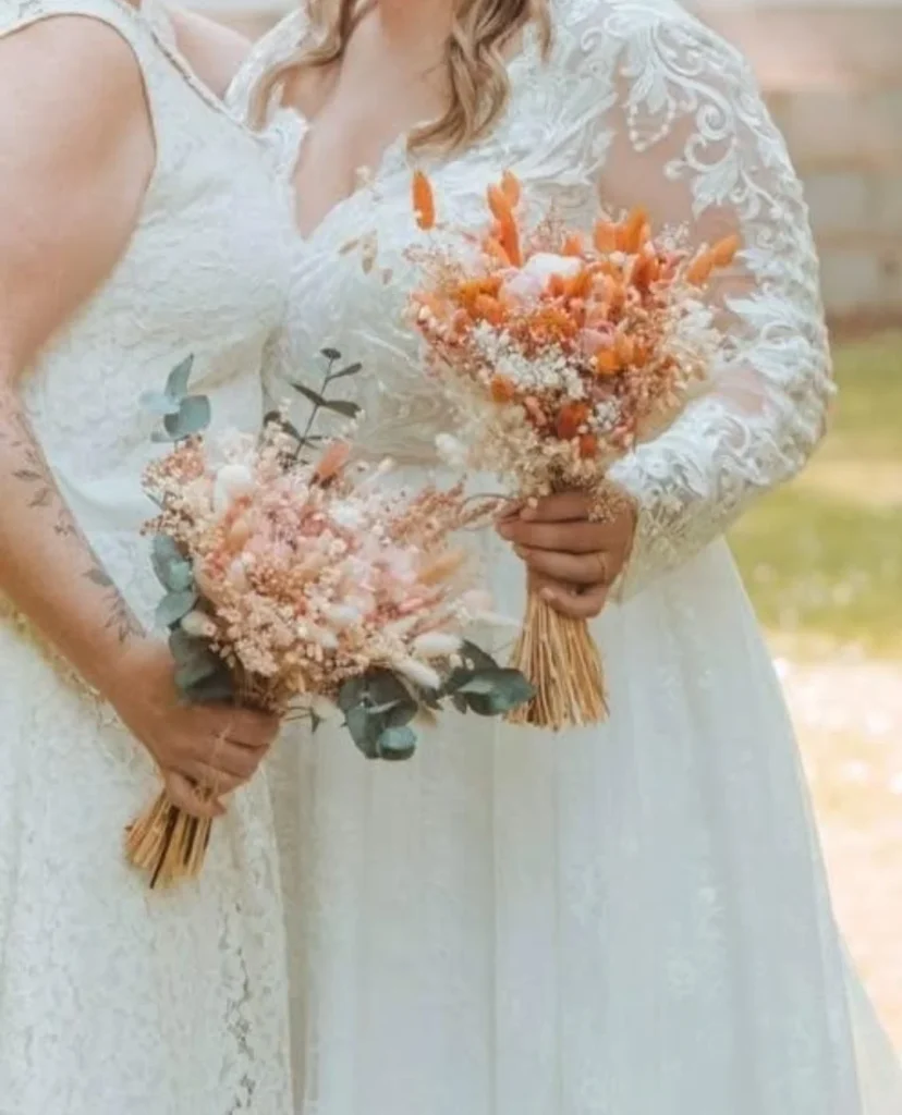 Duo de mariées tenant des bouquets de fleurs séchées, l’un dans des tons pêche et eucalyptus, l’autre en orange vif - Les pensées de Lily