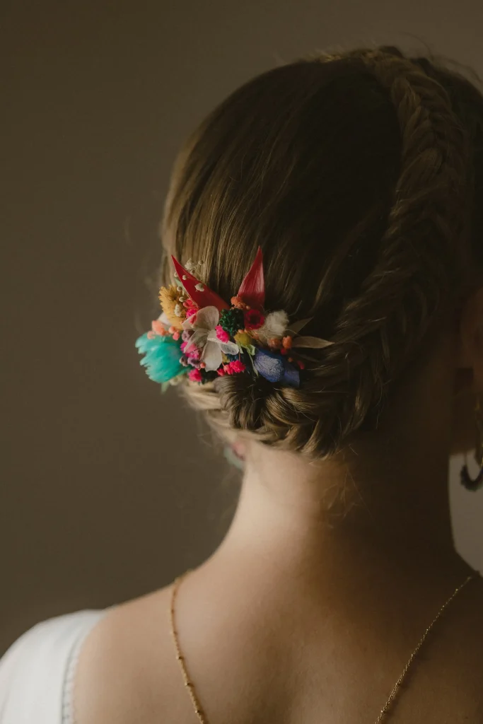 Chignon tressé de la mariée orné de fleurs séchées colorées en gros plan - Les pensées de Lily