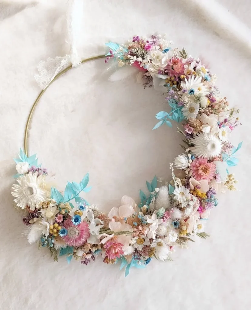 Couronne en fleurs séchées aux teintes pastel rose, bleu, blanc et jaune montée sur cercle doré, avec ruban en dentelle - Les pensées de Lily