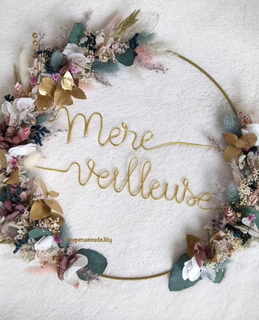 Couronne murale avec l'inscription “Mère Veilleuse” en fil doré, décorée de fleurs séchées pastel, touches de doré et eucalyptus sur fond blanc - Les pensées de Lily