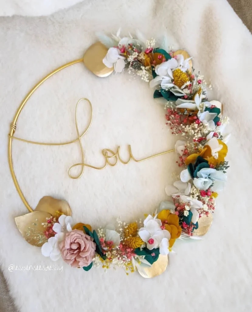 Couronne murale personnalisée avec le prénom Lou en fil doré et fleurs séchées blanches, moutarde, roses et eucalyptus sur fond doux - Les pensées de Lily