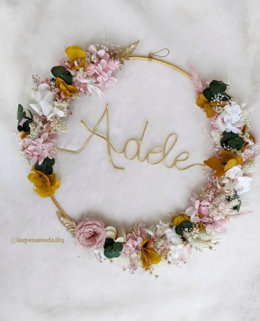 Couronne murale personnalisée avec le prénom Adèle en fil doré, fleurs séchées rose pâle, blanches, moutarde et eucalyptus sur fond clair - Les pensées de Lily
