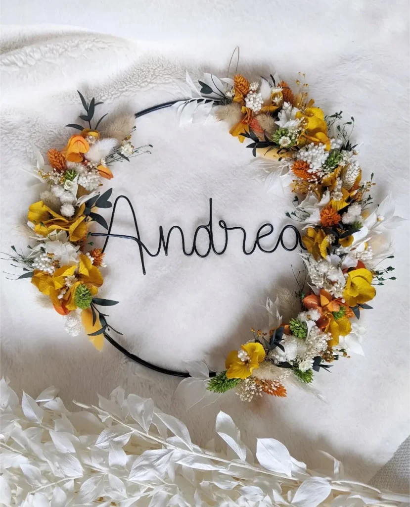 Couronne prénom Andrea en fil noir, décorée de fleurs séchées jaunes, blanches, terracotta et feuillage vert sur cercle noir - Les pensées de Lily