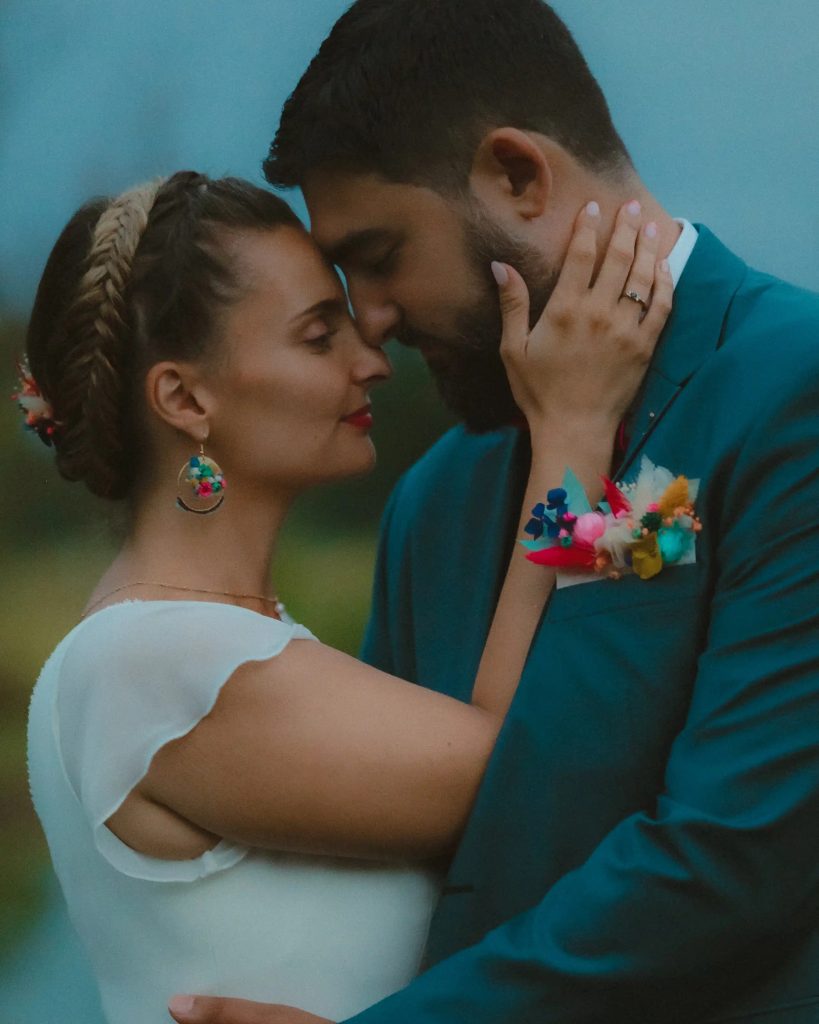 Mariée et marié front contre front, yeux fermés, bouquet de fleurs séchées en boutonnière et boucles d’oreilles assorties - Les pensées de Lily