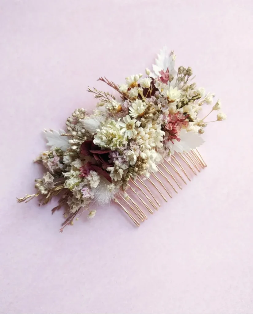 Peigne de mariage orné de fleurs séchées dans les tons blanc, beige, rose pâle et bordeaux, sur fond rose clair – Les pensées de Lily