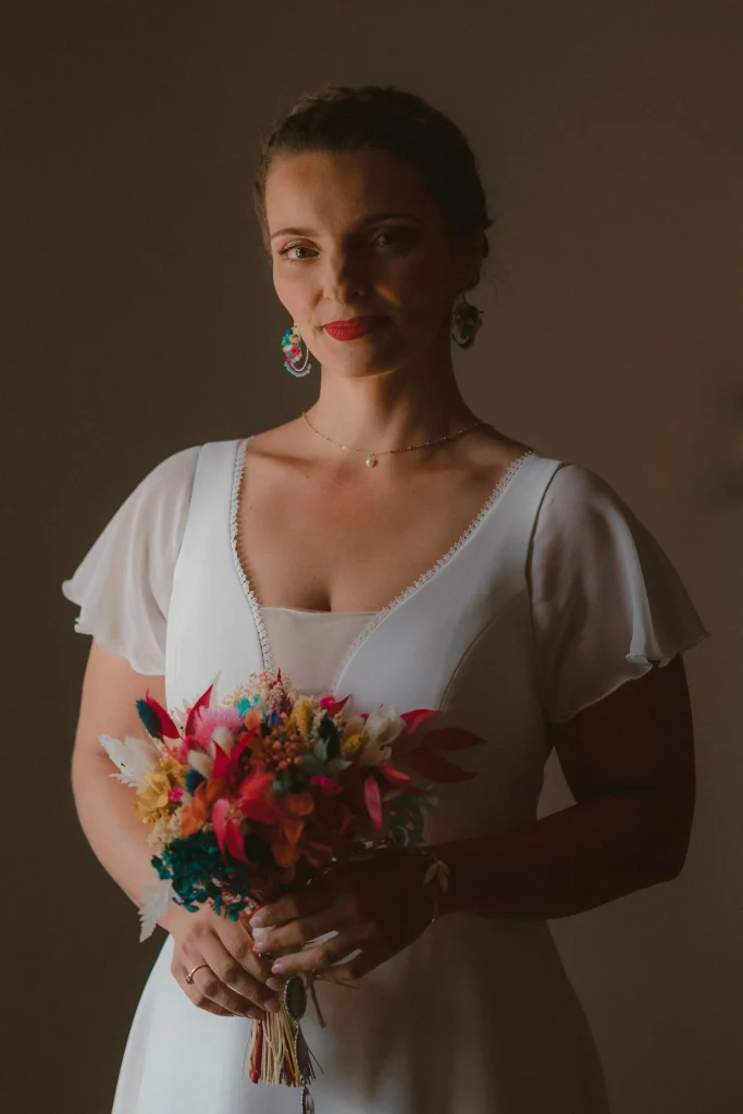Jeune mariée en robe blanche tenant un bouquet en fleurs séchées multicolores – Les pensées de Lily