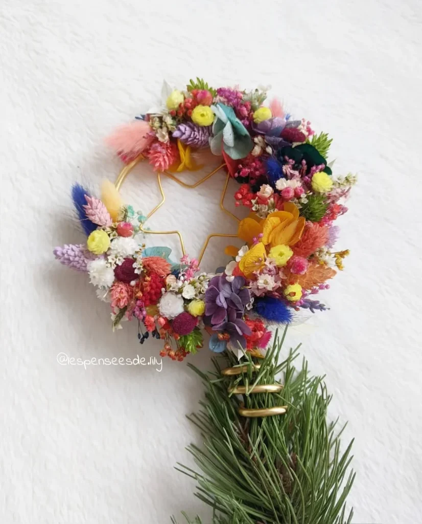 Topper de sapin composé de fleurs séchées multicolores sur structure en forme d’étoile et cercle doré, avec base en branches de pin – Les pensées de Lily