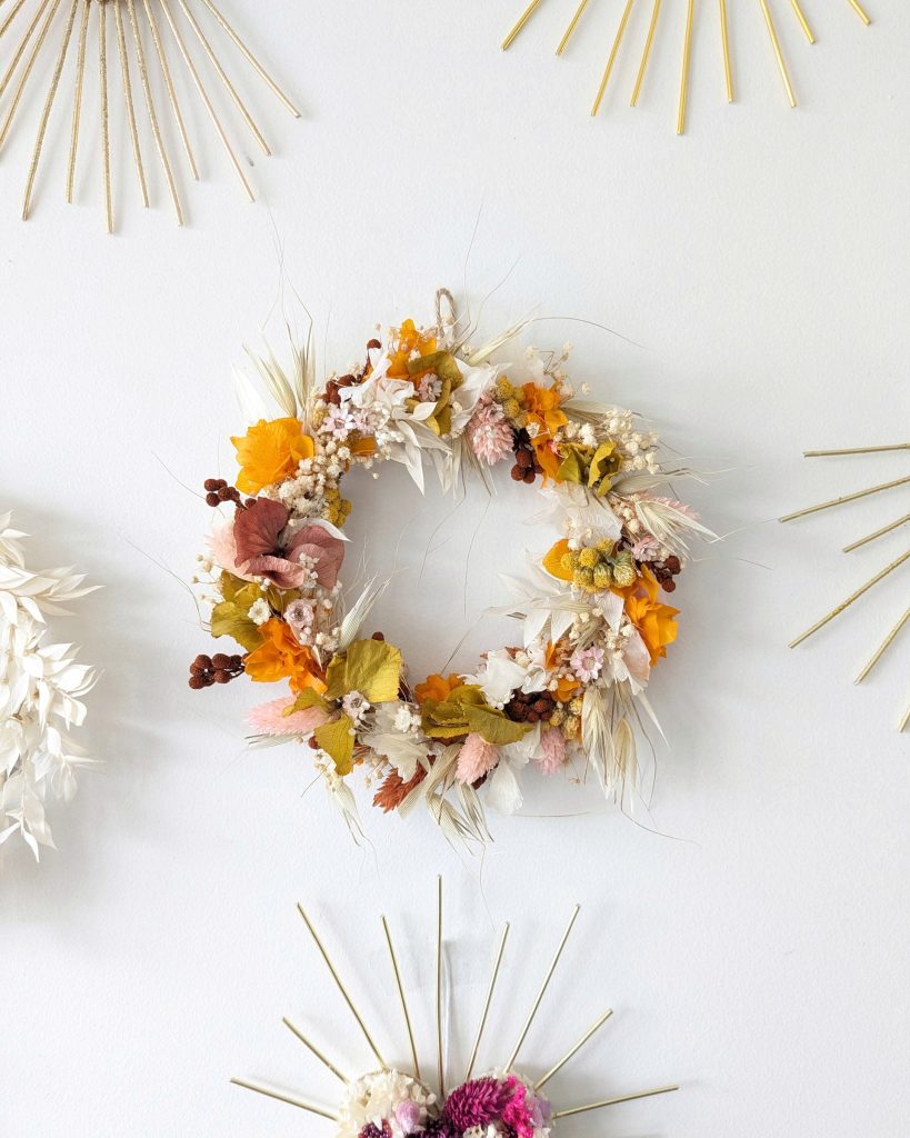 Petite couronne en fleurs séchées noemie, accrochée au mur