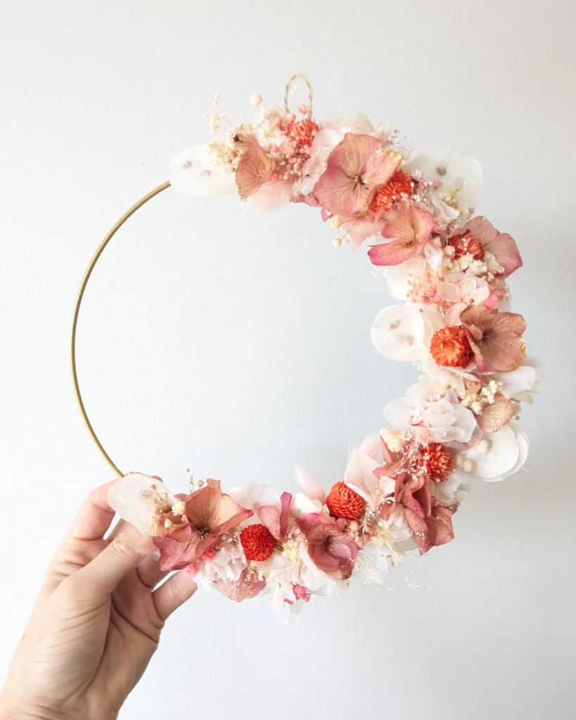 Couronne murale en fleurs séchées rose orange doré, tenue en main